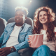 Rapaz e moça sentados no cinema vendo filme e comendo pipoca