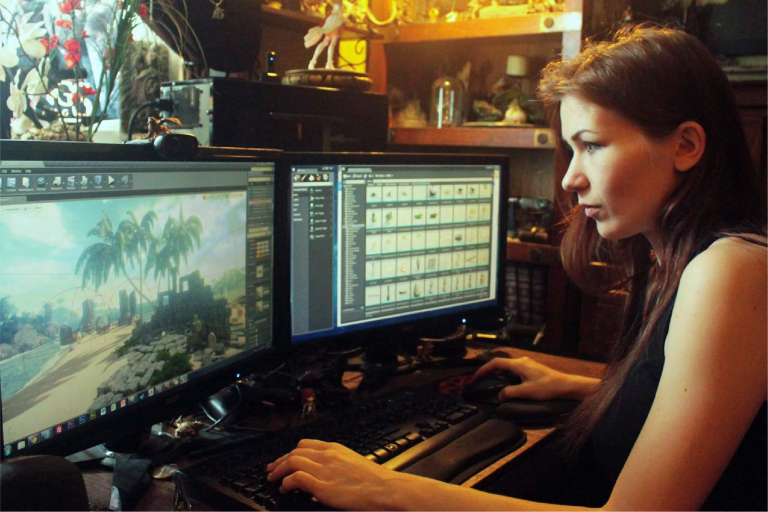 Moça trabalhando na área de Design de Games com duas telas ligadas.
