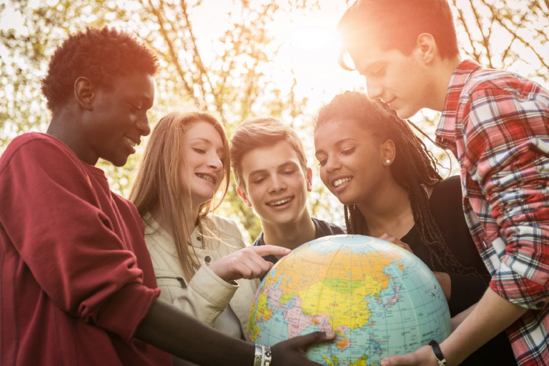 5 jovens estudantes olhando para um globo terrestre
