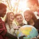 5 jovens estudantes olhando para um globo terrestre